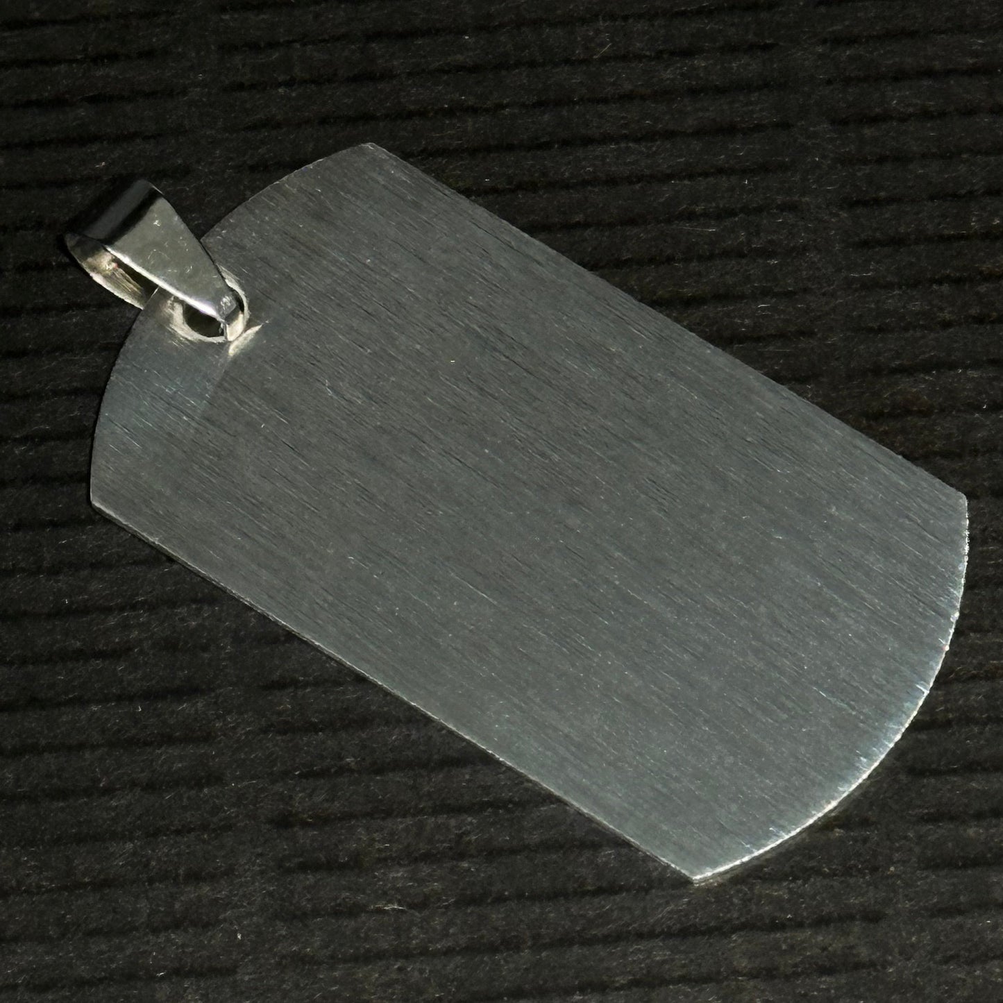 Metallic dog tag on a textured black background